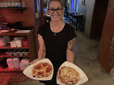 Server holding 2 specialty pizzas